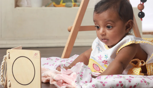 2 month old baby exploring wooden book during tummy time