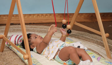 Baby trying hold the mobiles of the Baby Floor Gym