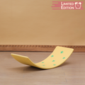 Yellow balancing board with green stars on a wooden floor against a beige wall.