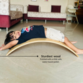 Child lying on a wooden balance board in a living room.