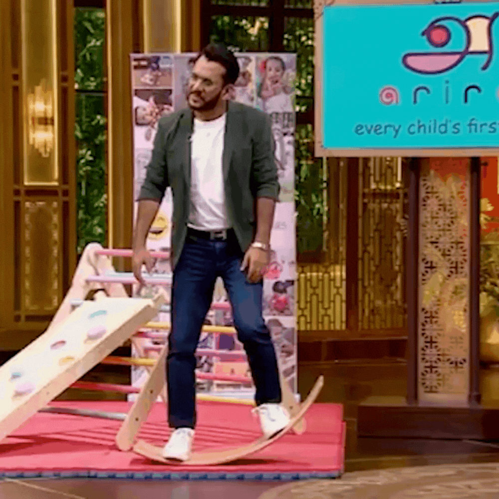 aman guptha, boats founder from shark tank season 1 rocking on Ariro's balancing board to demonstrate the stability of the product 