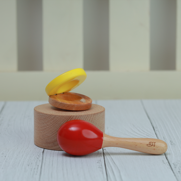 A handcrafted wooden baby percussion set featuring a yellow clapper and a red maraca designed for early musical play.
