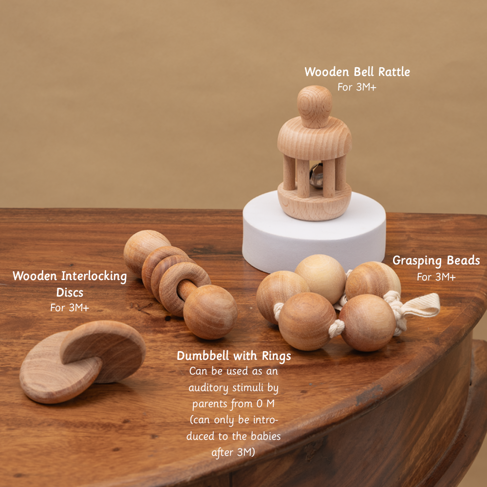 Montessori Baby Sensory Set – wooden bell rattle, interlocking discs, grasping beads, and dumbbell with rings – crafted for tactile and auditory exploration in infants aged 3 months and above.





