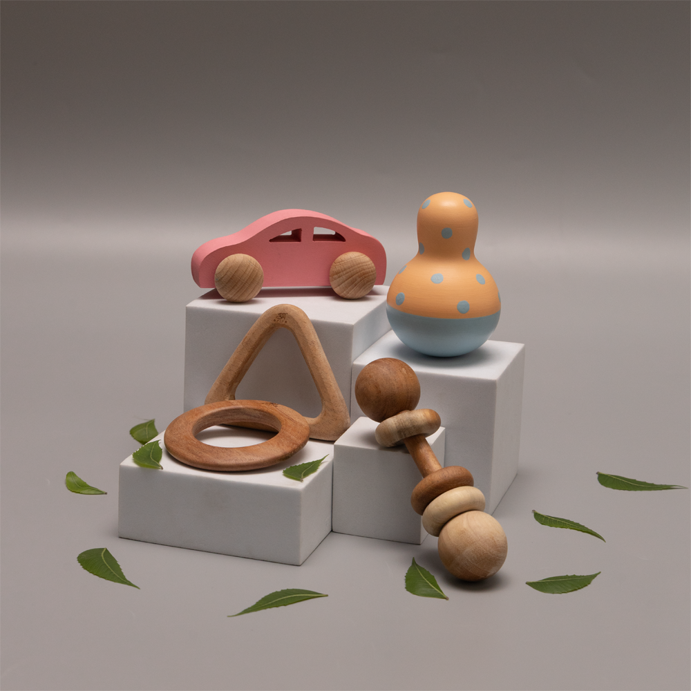 neem early play bundle  includes a pink toy car, a  wobble toy, a rattle, and teething rings, all made up of neem wood suggesting an eco-friendly and child-safe environment 






