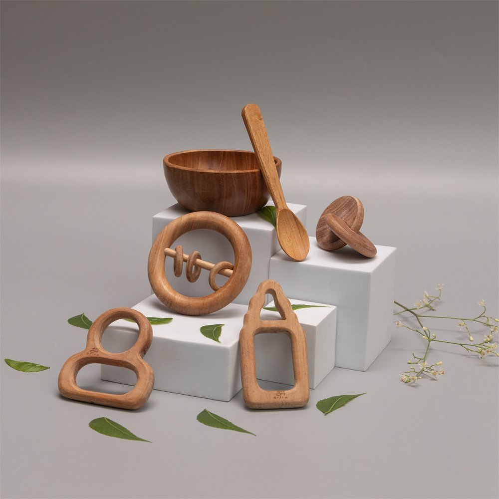 Neem Nurture Kit include interlocking disc , teethers , rattles , bowl and spoon  made  with  neem wood , suggesting an eco-friendly and child-safe environment 



