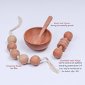 New Born Neem Wood Gift Box contains  natural wooden baby items, including grasping beads, a dumbbell with rings, and a bowl and spoon set for weaning.