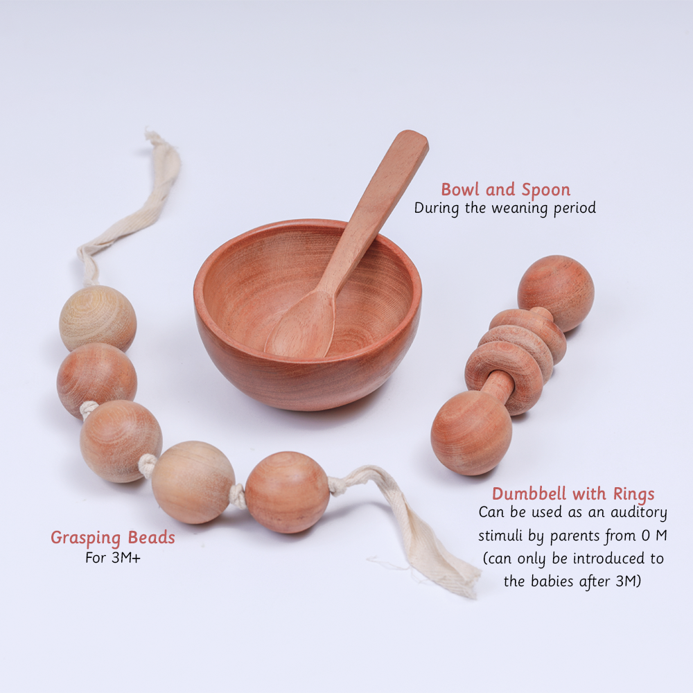 New Born Neem Wood Gift Box contains  natural wooden baby items, including grasping beads, a dumbbell with rings, and a bowl and spoon set for weaning.