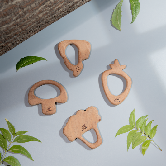 Wooden neem teethers shaped like fruits and vegetables designed for safe soothing and sensory exploration for babies.