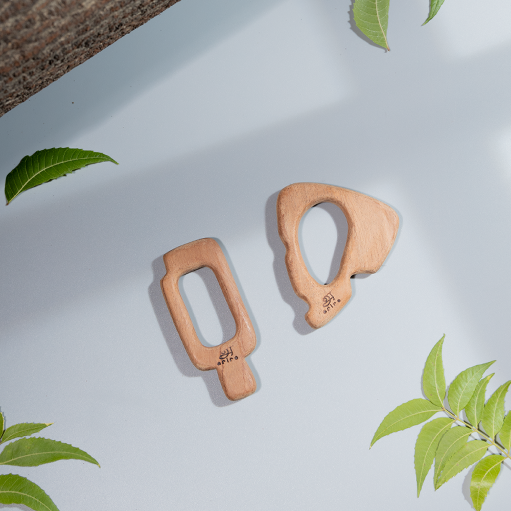 Two uniquely shaped neem wood teethers made up of  neem leaves, showcasing their smooth, natural finish and handcrafted quality.