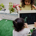Children drawing on the built-in blackboard of the Ariro Montessori learning tower creating a creative nook activity space.