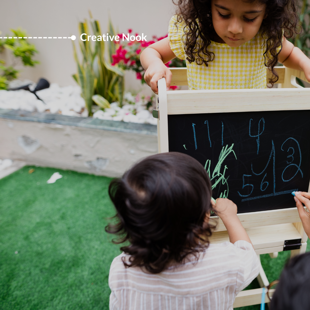 Children drawing on the built-in blackboard of the Ariro Montessori learning tower creating a creative nook activity space.