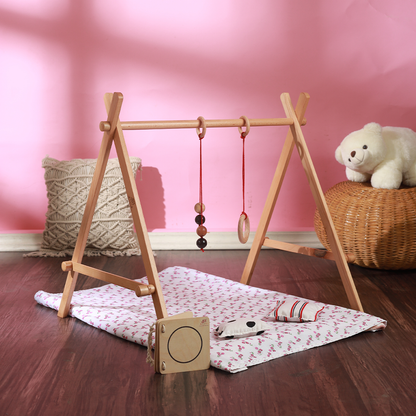 Ariro wooden Montessori baby floor gym with hanging mobiles placed on a soft mat, designed to support visual tracking, grasping and early motor development for babies from birth.