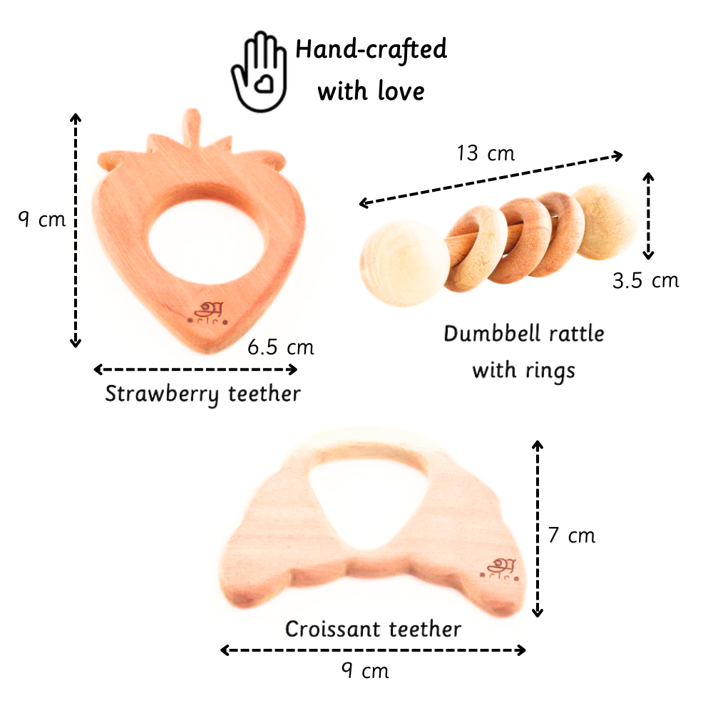 A handcrafted neem wood toy set featuring a strawberry teether, croissant teether, and dumbbell rattle with rings—designed for babies 3 months+ to support safe teething, sensory exploration, and grip development.
