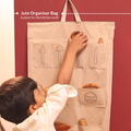 Child placing wooden tools into jute organiser bag for Little Chef’s Neem Kitchen Set, designed to store Montessori practical life kitchen tools neatly and accessibly