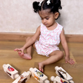 young child sitting on a wooden floor, engaged with wooden animal-themed rolling rattles, each decorated with vibrant animal images.
