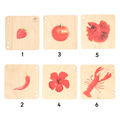  wooden puzzle tiles, all featuring a different red-colored object, including a strawberry, a tomato, fish , chilli , hibiscus and a lobster